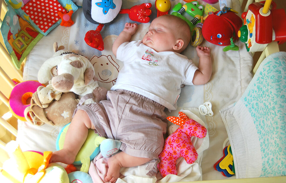Schlafendes Baby umgeben von Spielzeug