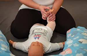 Eine Frau massiert die Füße einer Baby-Puppe