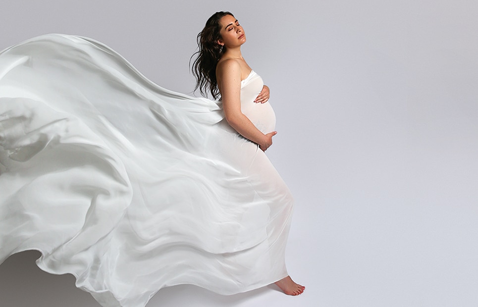 Eine schwangere Frau mit einem fließenden langen weißen wehenden Kleid
