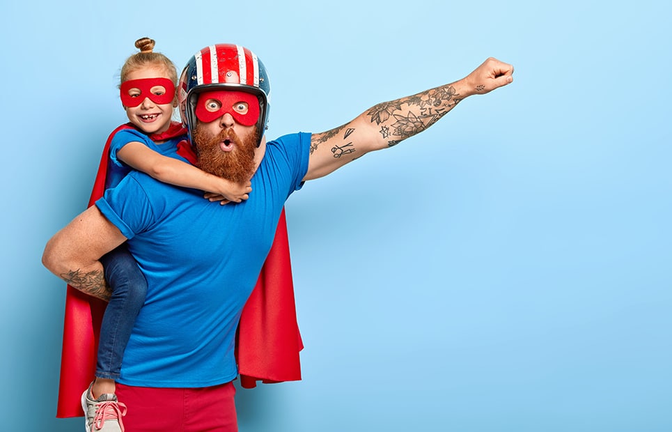 Ein Papa mit Tochter, beide sind mit einem Superhelden-Outfit verkleidet