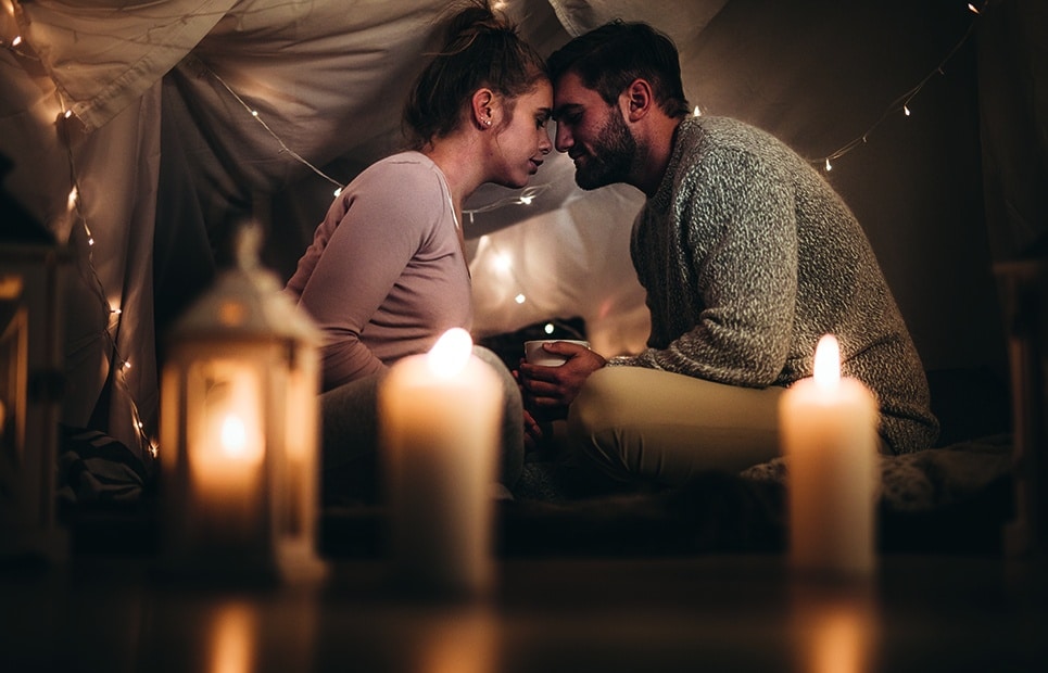Man sieht ein verliebtes Paar romantisch bei Kerzenschein